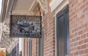 A sign reading "Marie Laveau Apartments" hangs on a brick wall with decorative metalwork above.